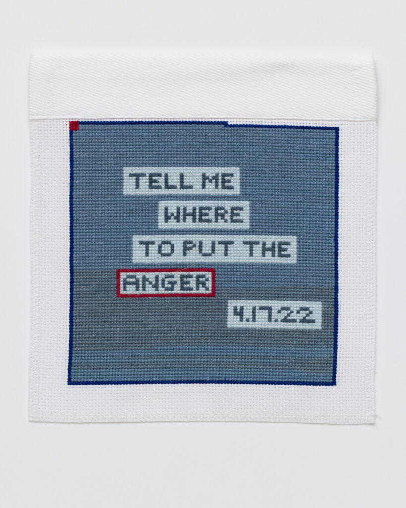 Blue stitching on a white square, with the words 