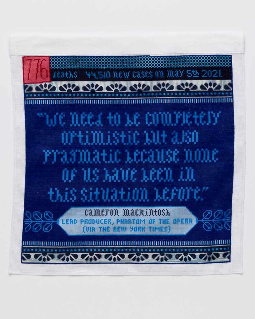 Cross stitch embroidery in blue threads with pink and red square in top left corner 
