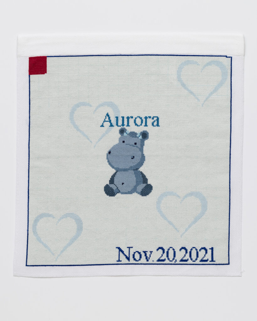 Cross stitch embroidery of a cartoon hippopotamus with the name 