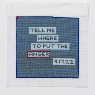 Photo by West Magyar Blue stitching on a white square, with the words "TELL ME WHERE TO PUT THE ANGER" inside lighter blue boxes. "4/17/22" is in the lowest light blue box. The box around "ANGER" is outlined in red.