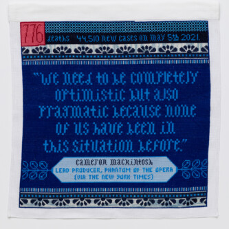 Photo by Wes Magyar Cross stitch embroidery in blue threads with pink and red square in top left corner "776" written inside the square. The top strip of the piece reads "deaths 44, 510 new cases on may 5th 2021." below that is a pattern of scallops in dark blue, with a line of blue dots and stripes beneath it. In the middle is a quote: "we need to be completely optimistic but also pragmatic because none of us have been in this situation before." In the bottom is a light blue diamond shape with "Cameron Mackintosh Lead Producer, Phantom of the Opera (via the New York Times) written. The stripe/dot/scallop pattern is repeated at the bottom.